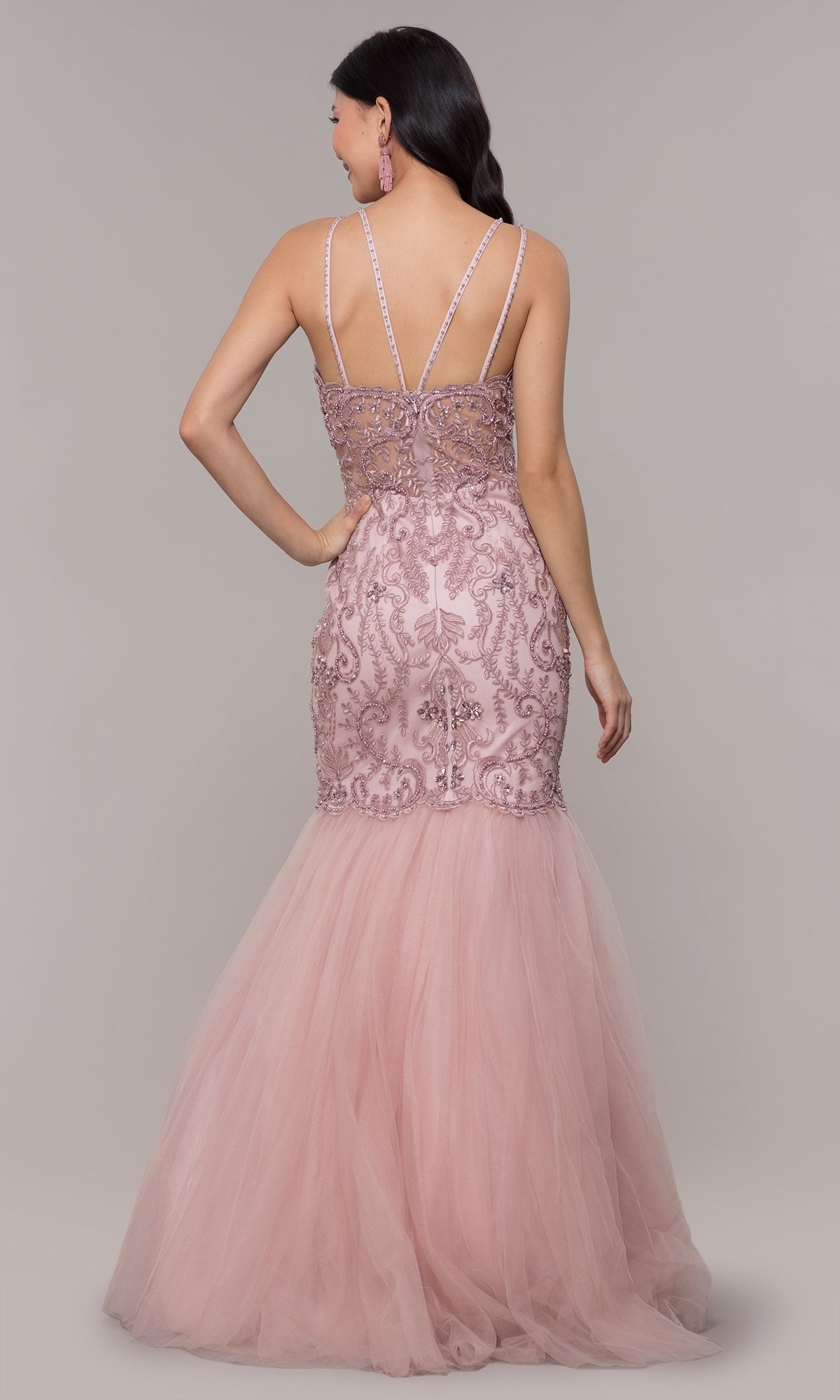 A woman is seen from the back wearing the Embroidered Tight Sweetheart Mermaid Prom Dress 8352 in blush pink, featuring lace and sequin details, double spaghetti straps, and a tulle mermaid skirt.